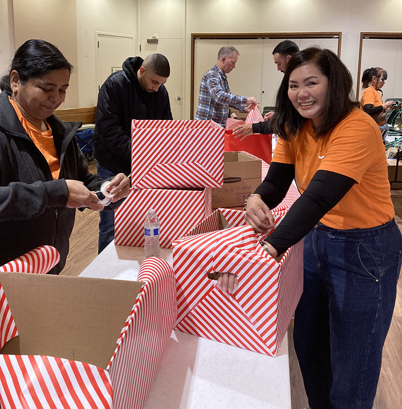 Amazon volunteers helping to wrap holiday boxes for homebound seniors
