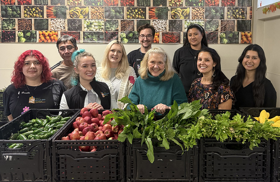 Group of people in front of vegetables in bins